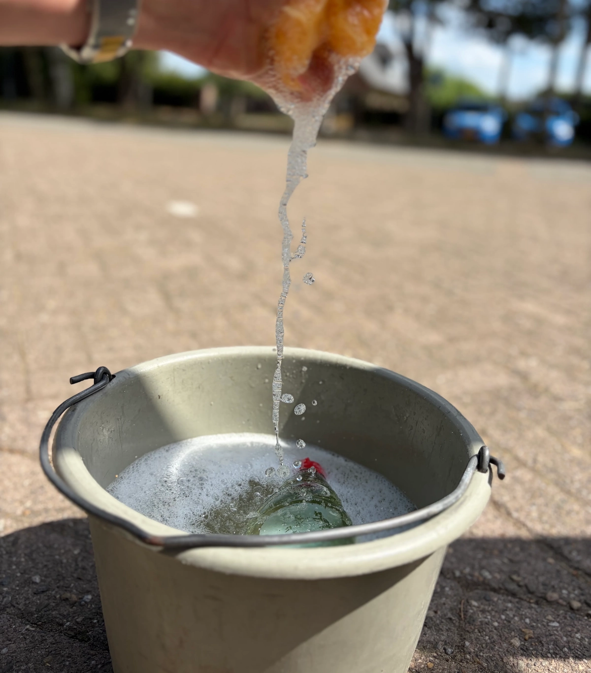 Emmer met schuim en spons voor het wassen van ramen bij een bedrijfspand
