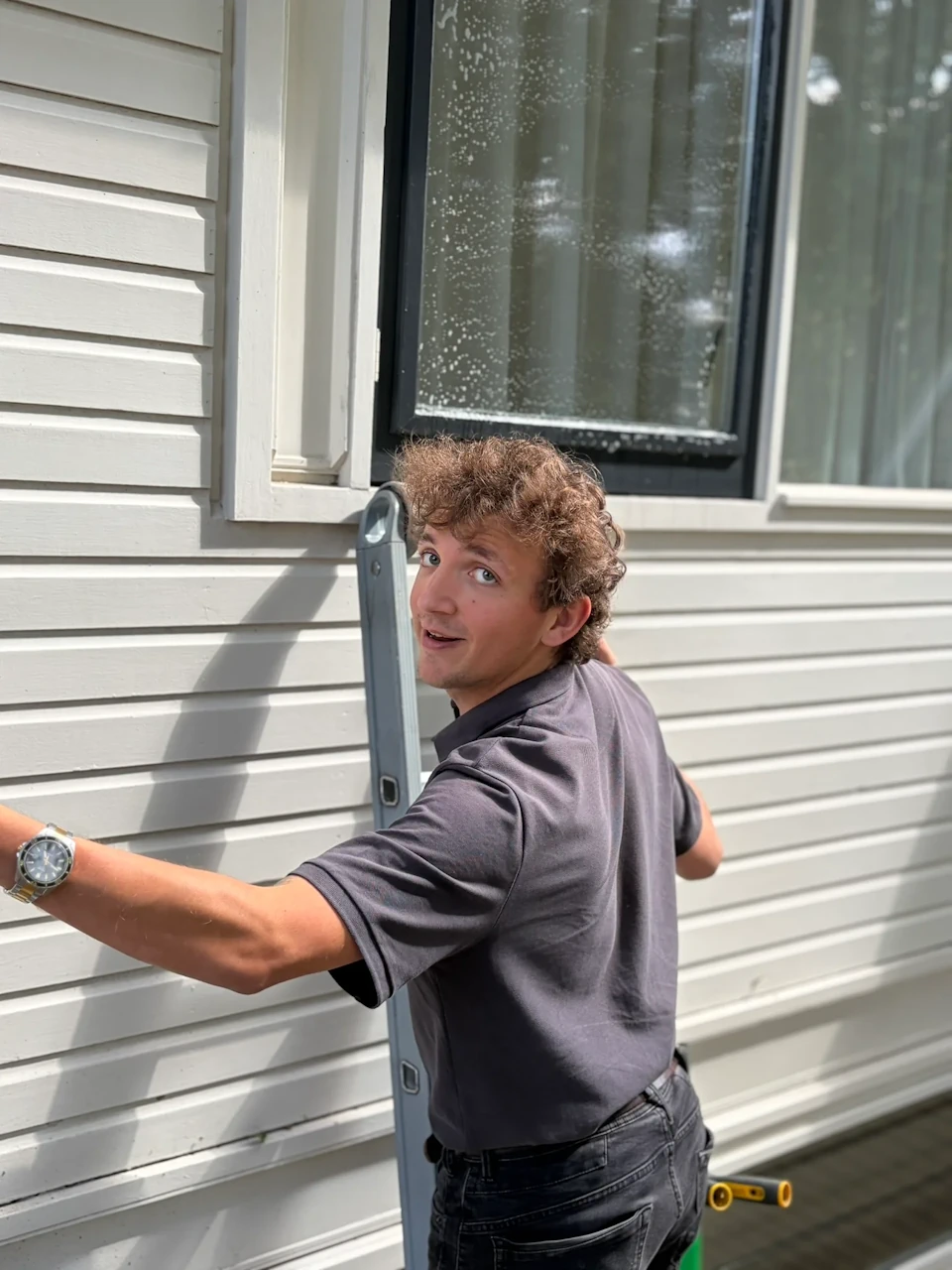 Teun van Kijkschoon op een ladder met een spons in zijn hand, klaar om ramen te wassen.